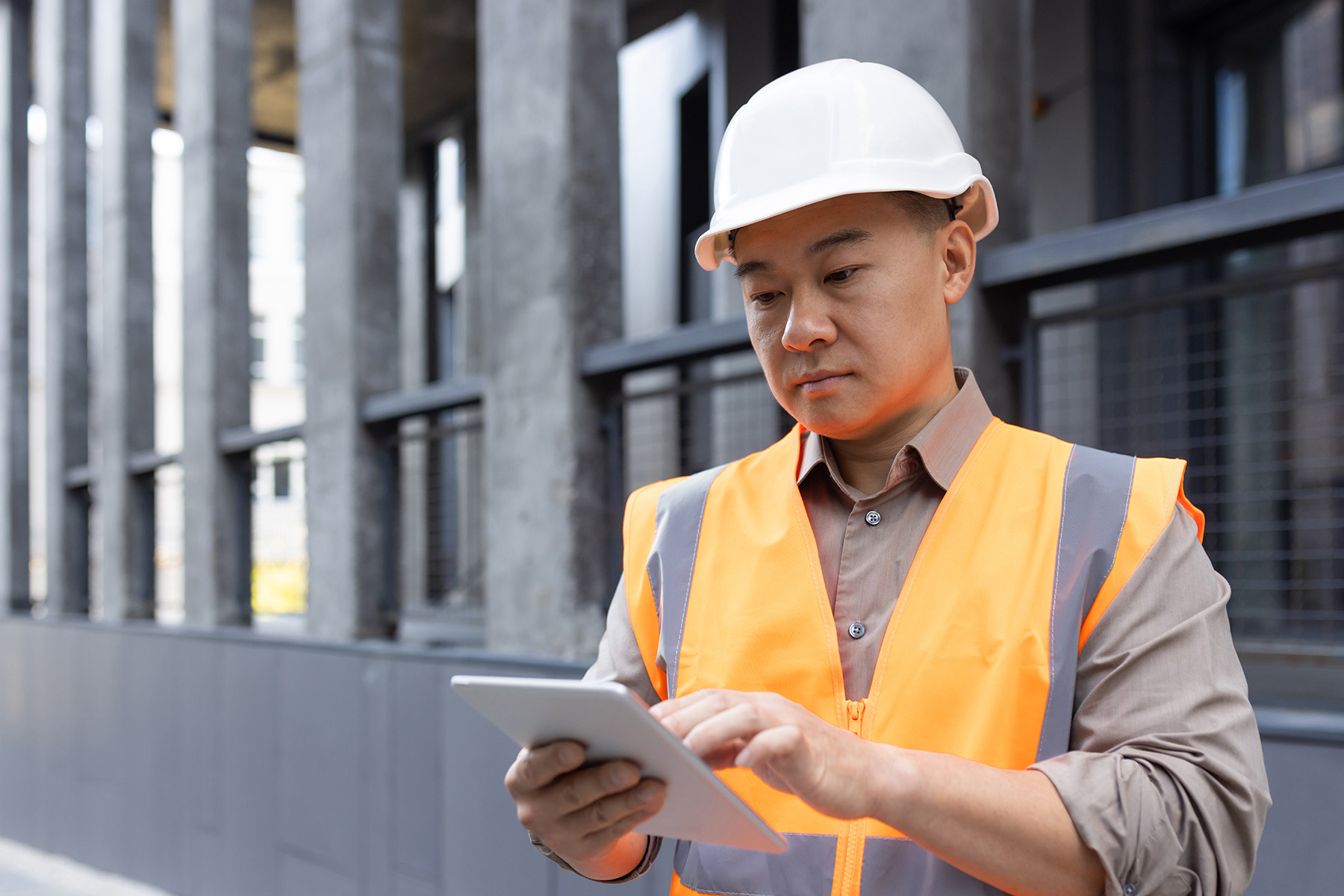 Construction business owner reviewing job cost reports on a tablet at an active job site